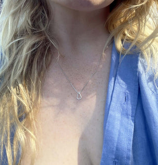 Woman wearing a silver hollow drop pendant necklace, showcasing its elegant design and reflective shine.