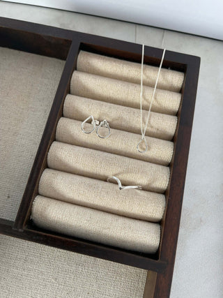 Organized display of silver hollow drop pendant necklace and earrings on a fabric-lined jewelry tray.