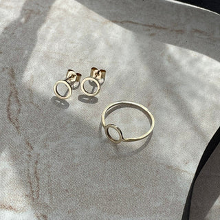 Gold ring and earrings on a marble surface
