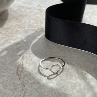 Silver ring on a textured surface with a black ribbon
