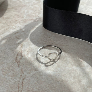 Silver ring on a textured surface with a black ribbon