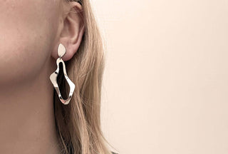 Close-up of a model wearing KONGSTRUP sculptural solid silver earrings, showcasing their unique design and elegance.