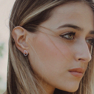 Close-up of a woman wearing a delicate earring with a blurred natural background