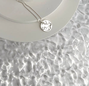 Dominga-silver-hammered-disc-pendant-necklace-flatlay-by-Marie-Beatrice-Gade