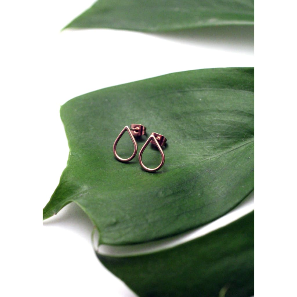 Filippa Mini 9 ct red gold earrings by eco jeweller M of Copenhagen laid out on a leaf at an angle