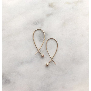 Gabrielle Cross over gold earrings by eco jeweller M of Copenhagen placed on marble from front