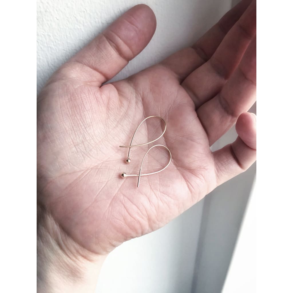 Cross over gold earrings Gabrielleby eco jeweller M of Copenhagen held in hand