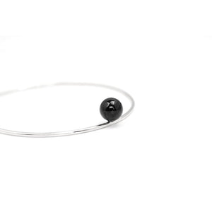 Positano bangle by M of Copenhagen made with recycled silver and a natural obsidian bead on white background