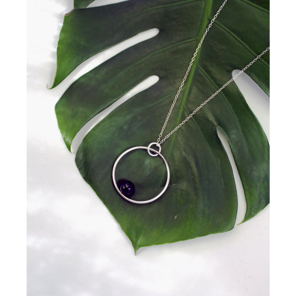 Positano necklace by M of Copenhagen made with recycled silver and onyx posed on a leaf